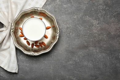 Glass of milk and nuts on grey background, top view