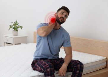 Image of Man suffering from neck pain after sleeping on uncomfortable mattress at home