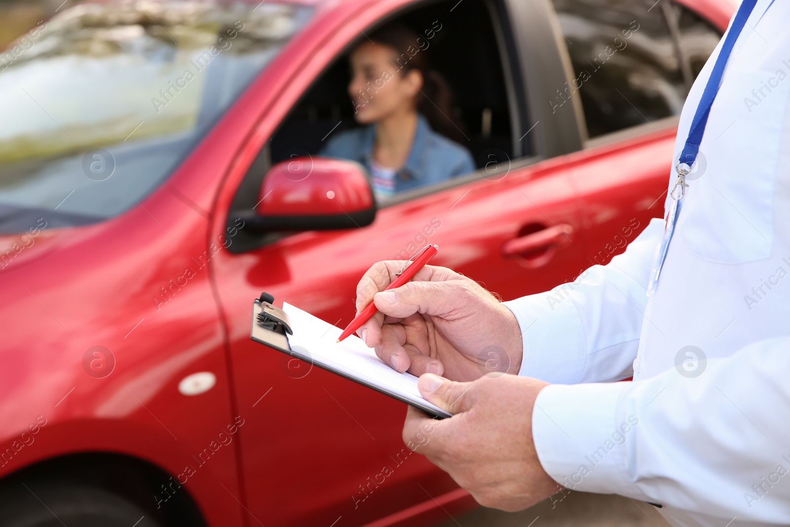 Photo of Instructor near woman in car, outdoors. Passing driving license exam