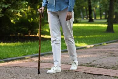 Photo of Senior woman with walking cane in park, closeup