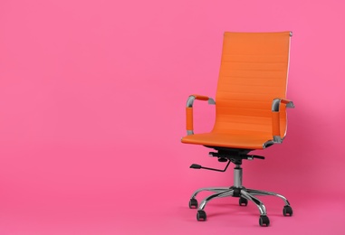 Comfortable office chair on pink background, space for text