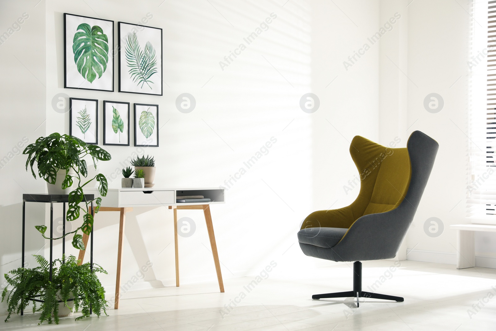 Photo of Stylish room interior with comfortable armchair and paintings of tropical leaves