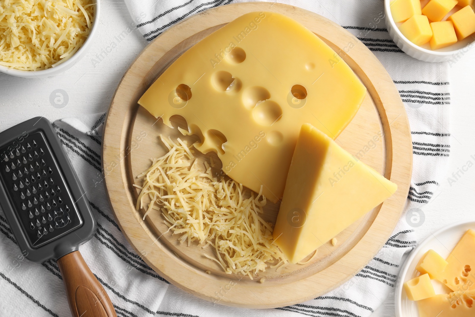 Photo of Grated, cut cheese and grater on white wooden table, flat lay