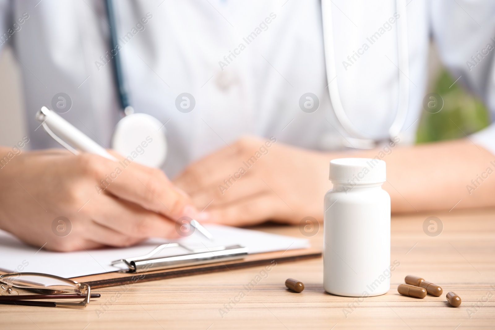 Photo of Closeup view of doctor working at desk in office, focus on pills. Medical service