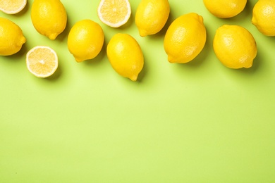 Flat lay composition with whole and sliced lemons on color background