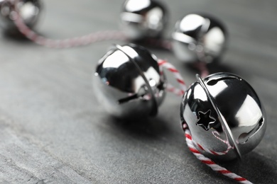 Shiny silver sleigh bells on grey stone table, closeup. Space for text