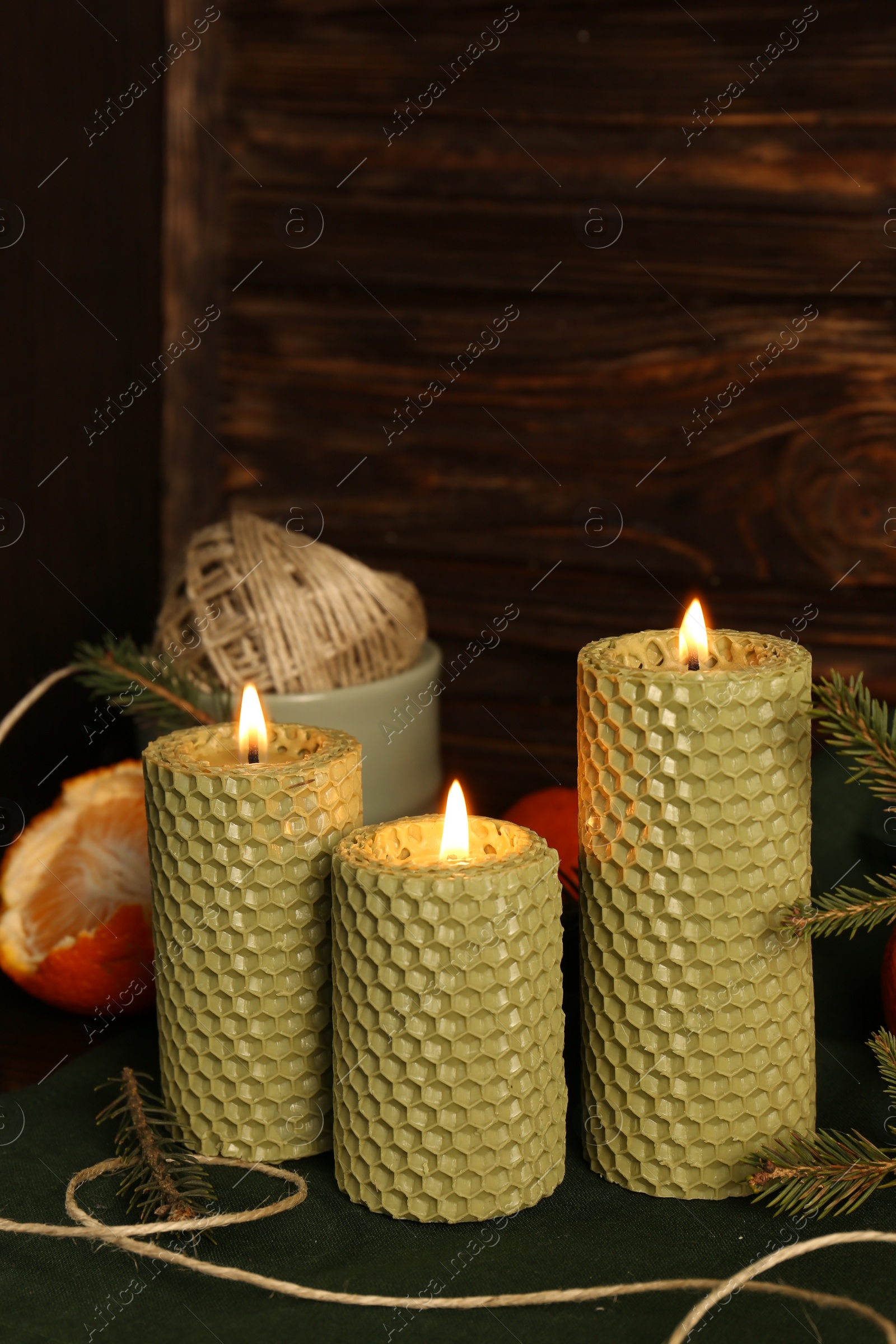 Photo of Beautiful burning beeswax candles, rope and tangerines on table