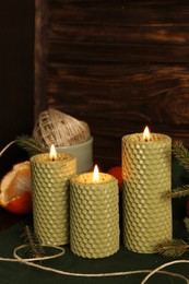 Beautiful burning beeswax candles, rope and tangerines on table