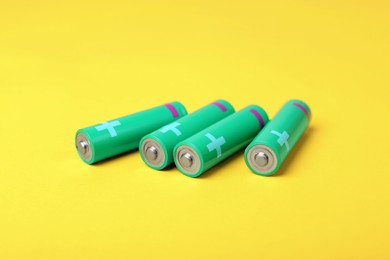 New green AA batteries on yellow background