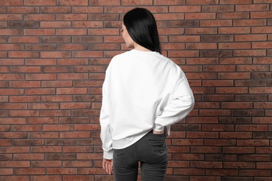 Photo of Young woman in sweater at brick wall. Mock up for design