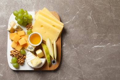 Photo of Board with different kinds of delicious cheese and snacks on marble background, top view. Space for text