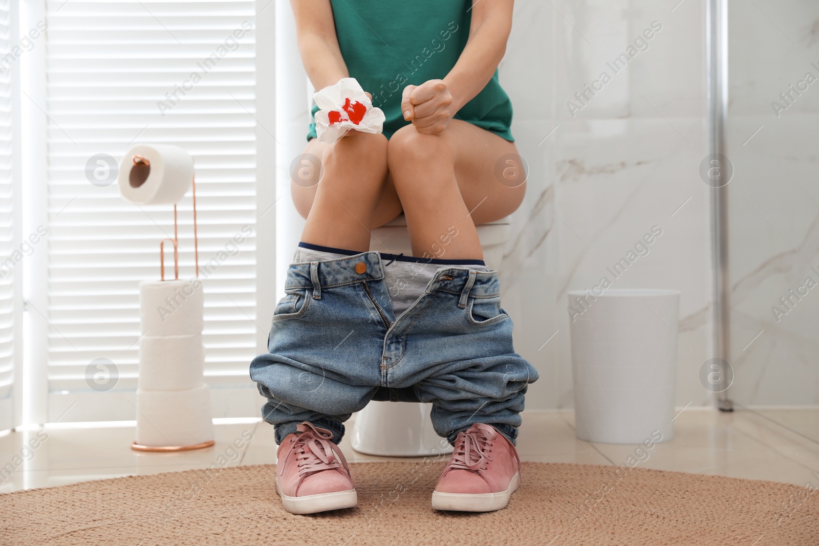 Photo of Woman holding toilet paper with blood stain in rest room, closeup. Hemorrhoid concept