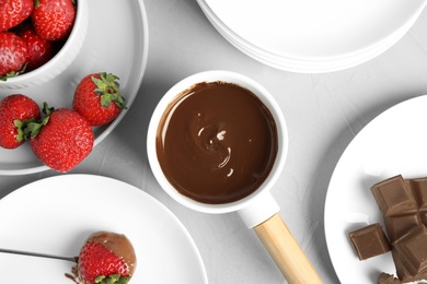 Photo of Flat lay composition with fondue pot and chocolate on grey table