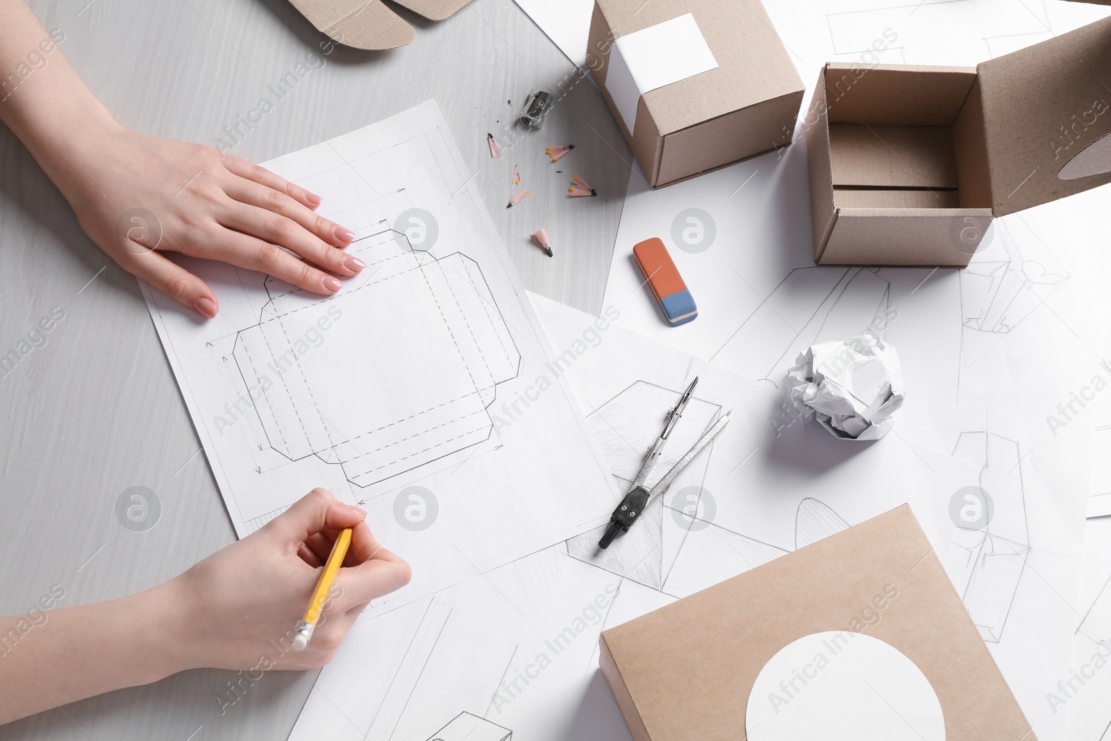 Photo of Woman creating packaging design at light wooden table, top view