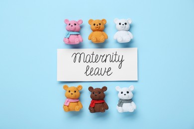 Photo of Card with phrase Maternity Leave and toys on light blue background, flat lay