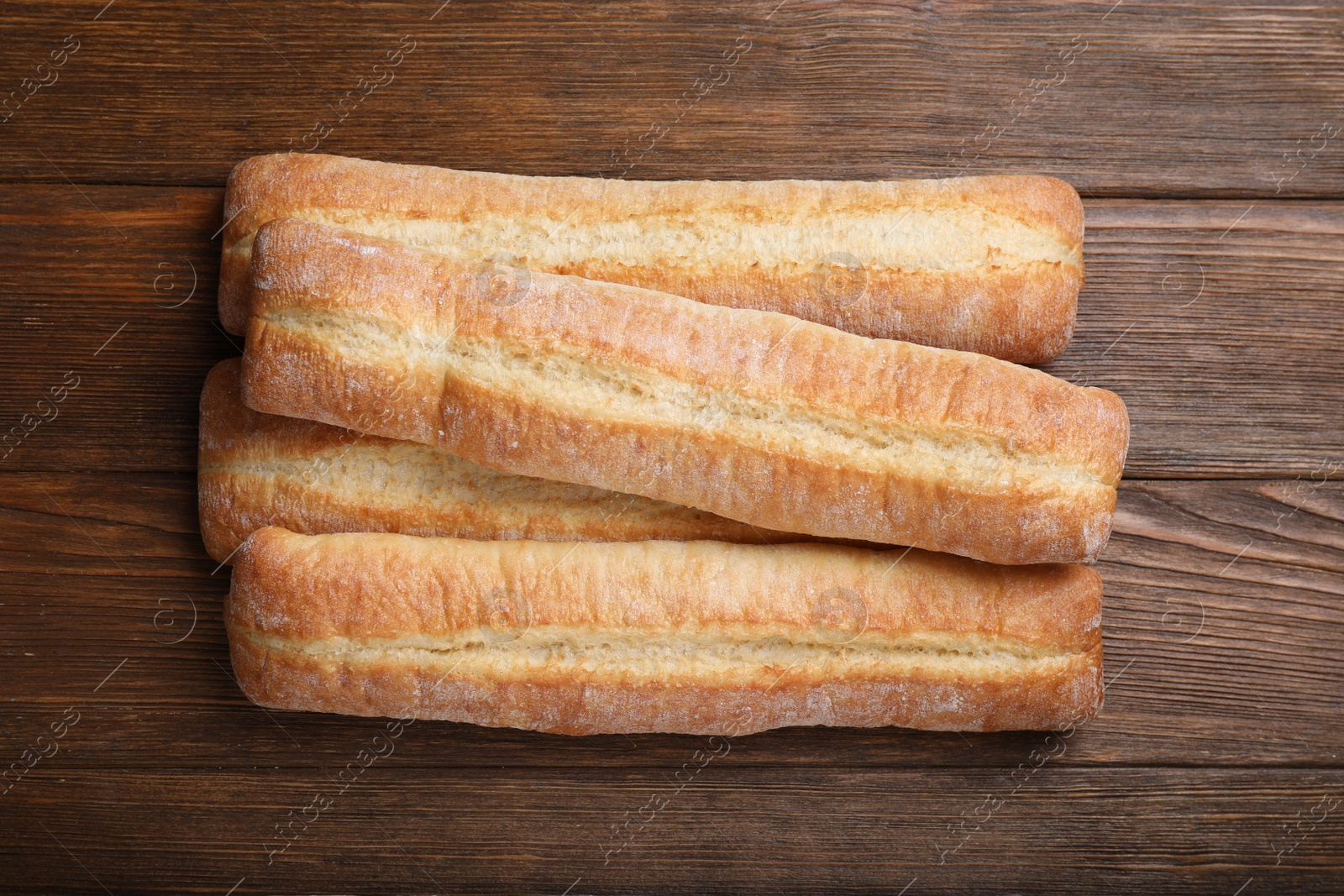 Photo of Tasty baguettes on wooden table, top view