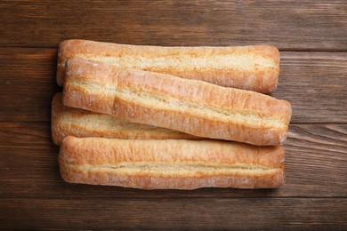 Photo of Tasty baguettes on wooden table, top view