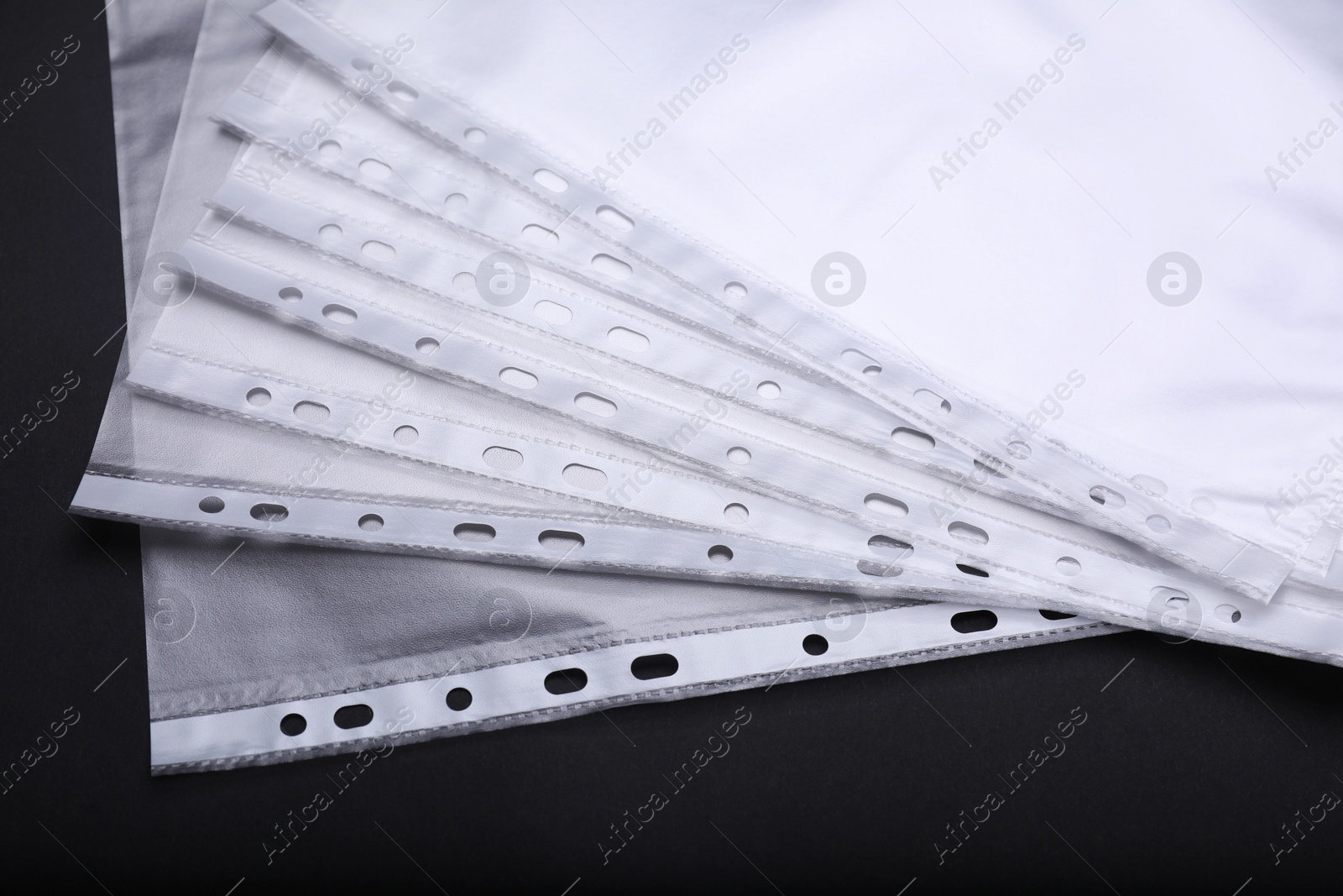 Photo of Many punched pockets on black background, closeup