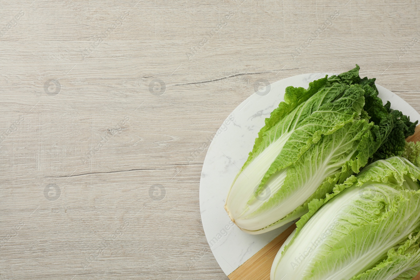 Photo of Fresh ripe Chinese cabbages on white wooden table, top view. Space for text