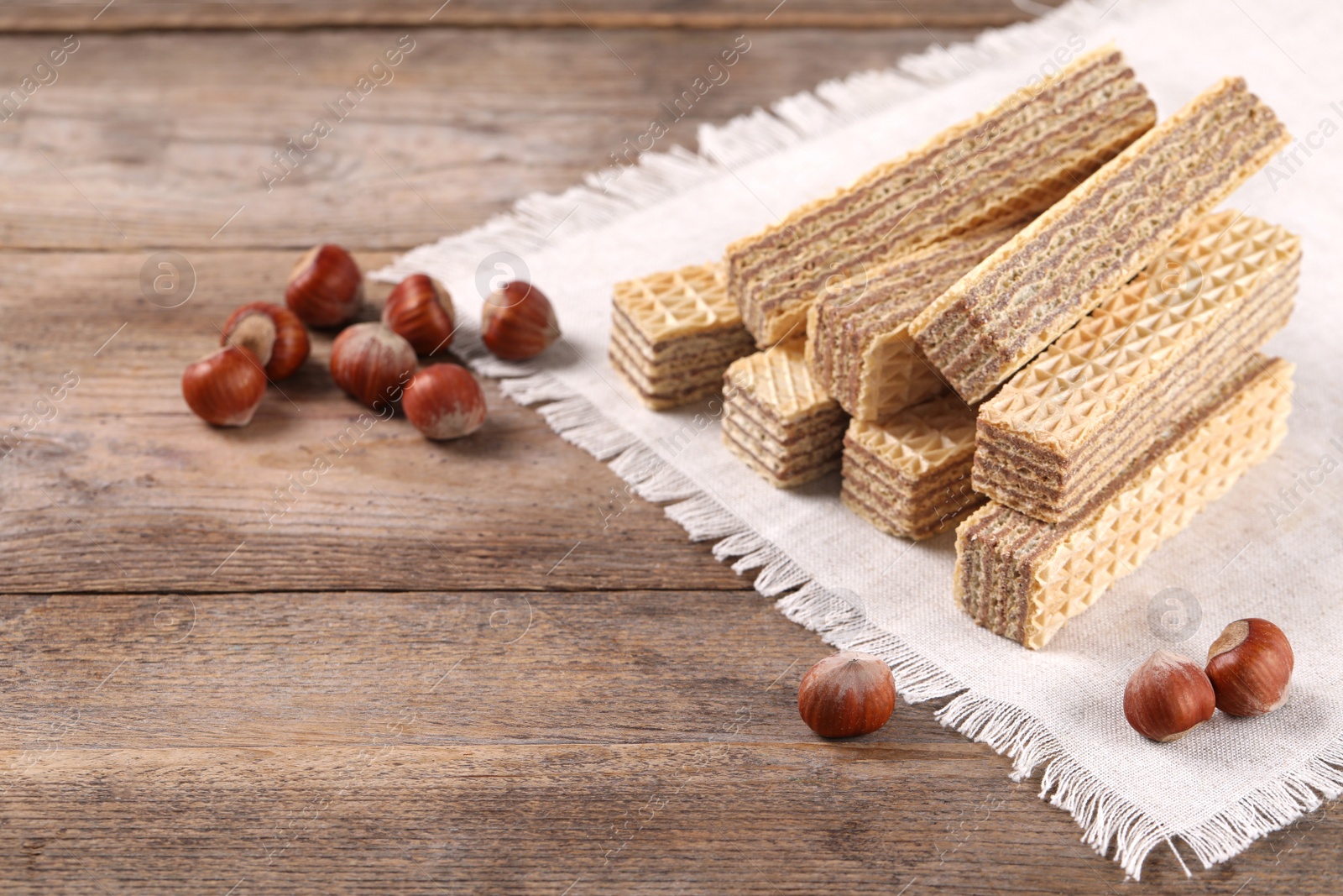 Photo of Delicious wafers with hazelnuts on brown wooden background