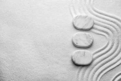 Top view of white stones on sand with pattern, space for text. Zen, meditation, harmony