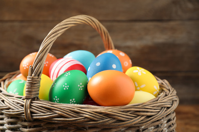 Photo of Colorful Easter eggs in basket on wooden background, closeup