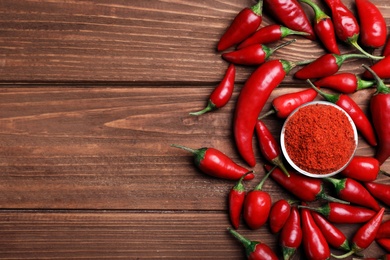 Photo of Flat lay composition with fresh chili peppers, powder and space for text on wooden background