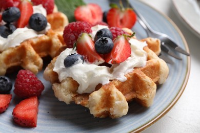 Delicious Belgian waffles with fresh berries and whipped cream on white table, closeup