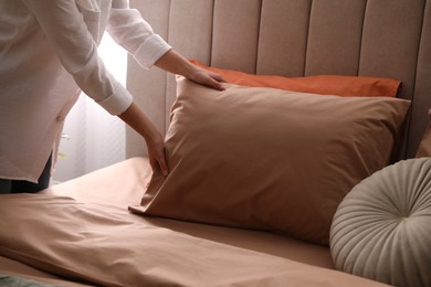 Woman making bed with stylish linens in room, closeup