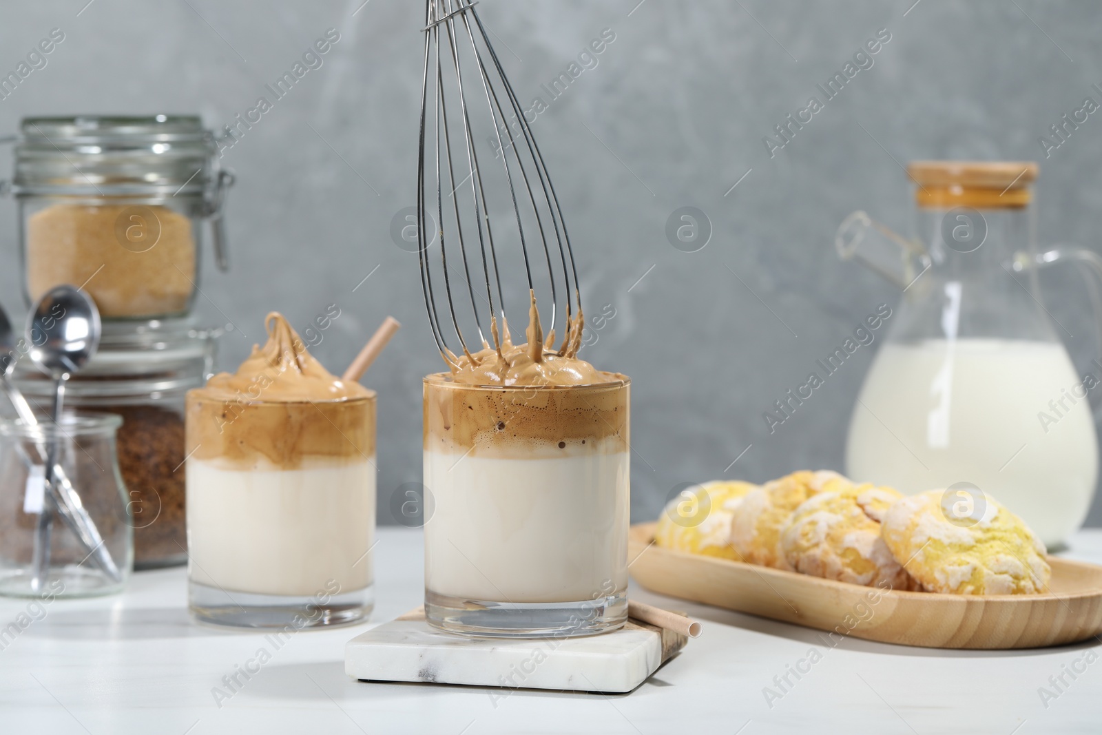 Photo of Putting cream for dalgona coffee into glass on white table