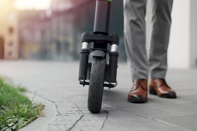 Photo of Businessman with modern kick scooter on city street, closeup. Space for text