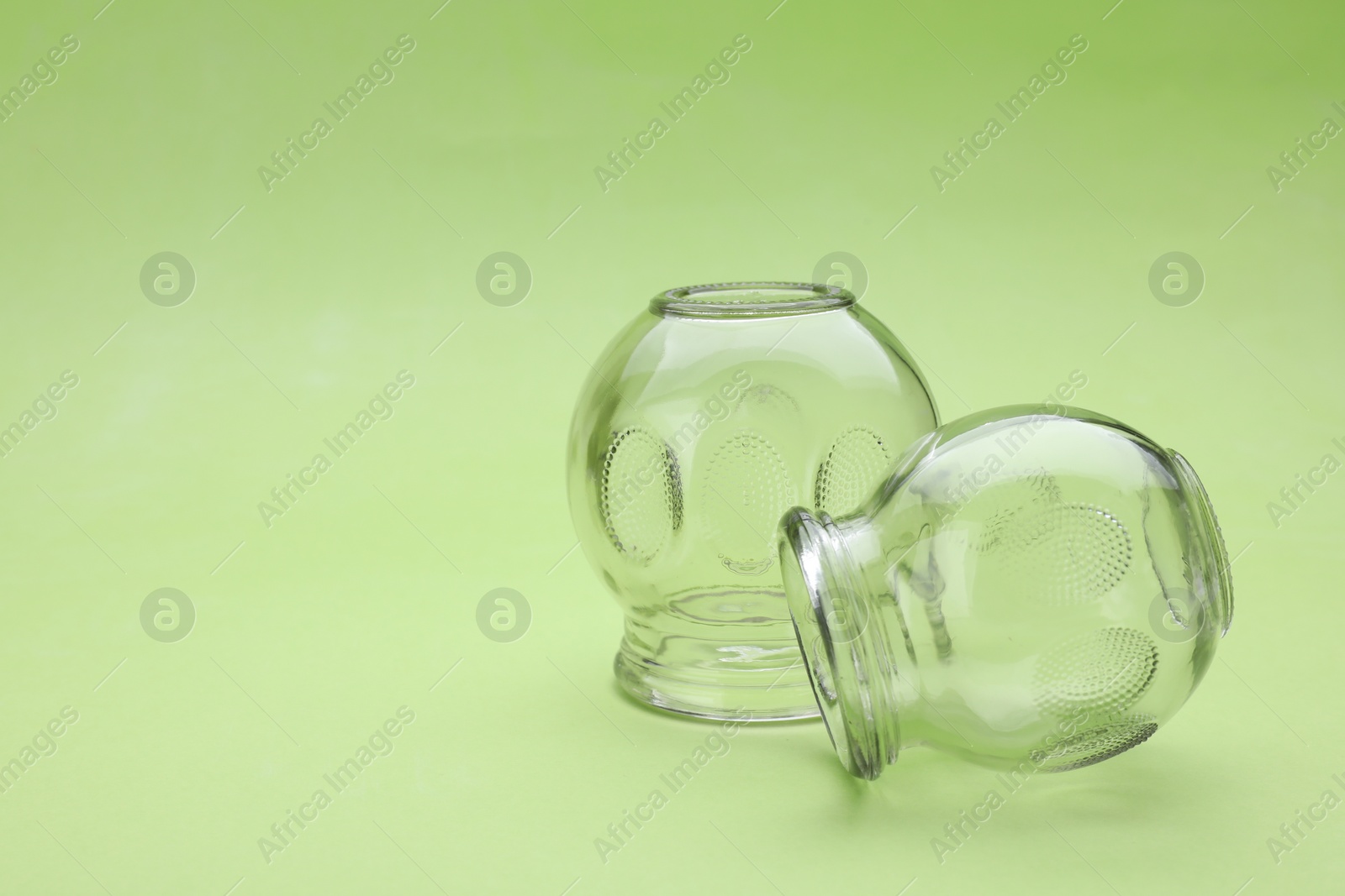 Photo of Glass cups on light green background, closeup with space for text. Cupping therapy