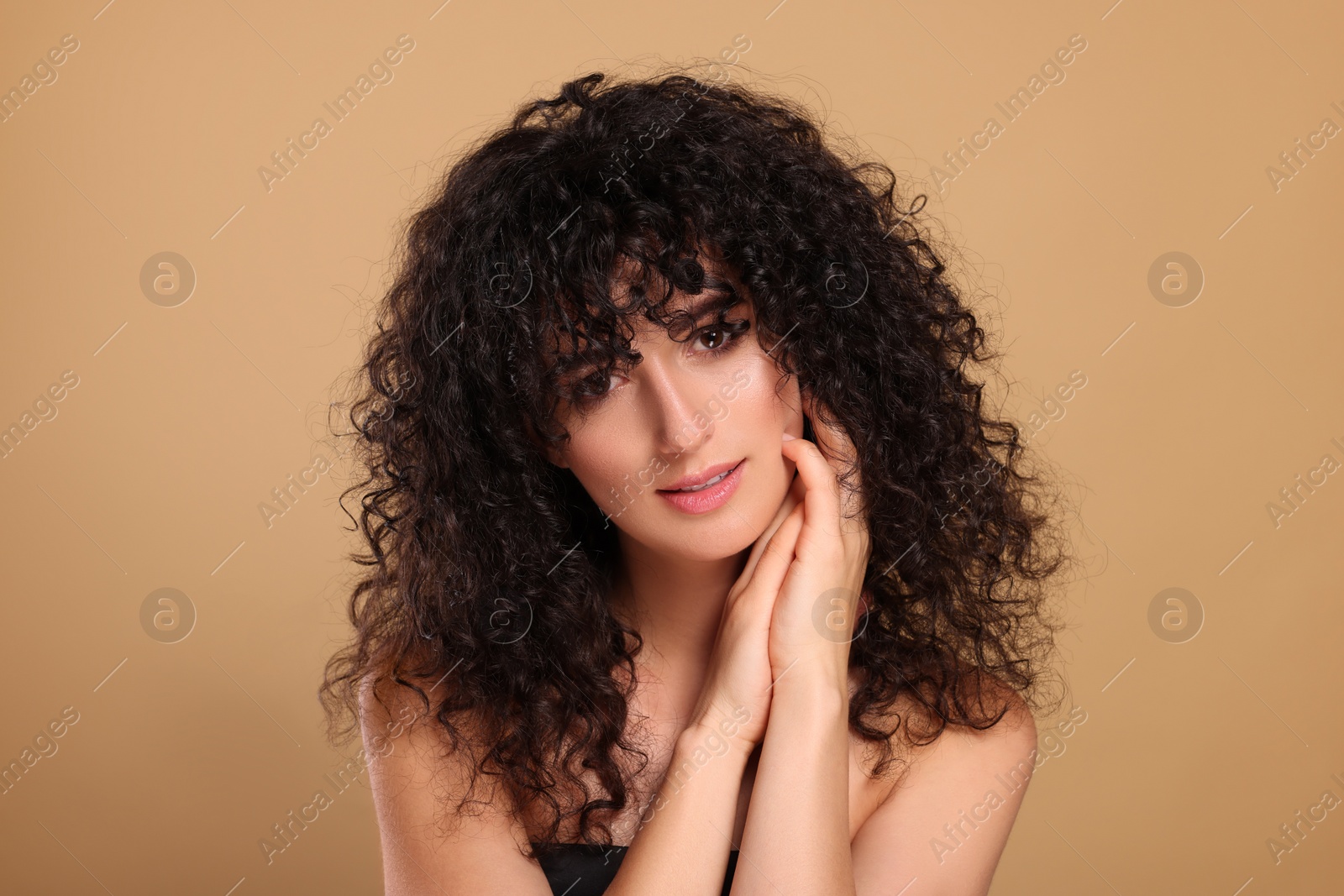 Photo of Beautiful young woman with long curly hair on beige background