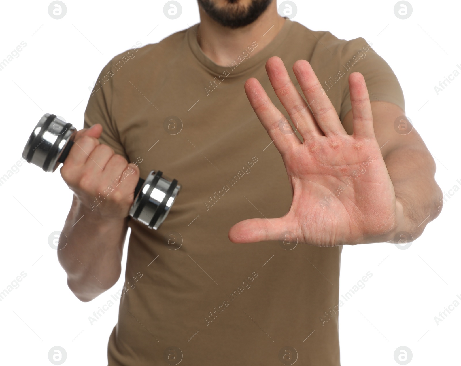 Photo of Sporty man with dumbbell suffering from calluses on hands against white background, closeup