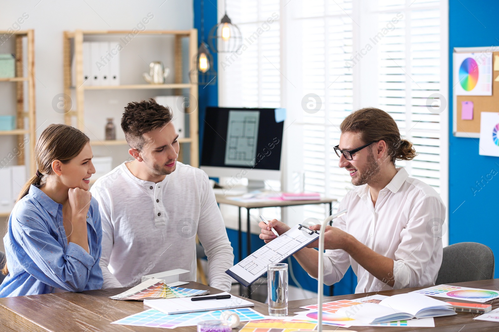 Photo of Interior designer consulting young couple in office