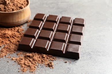 Photo of Chocolate bar and cocoa powder on grey background