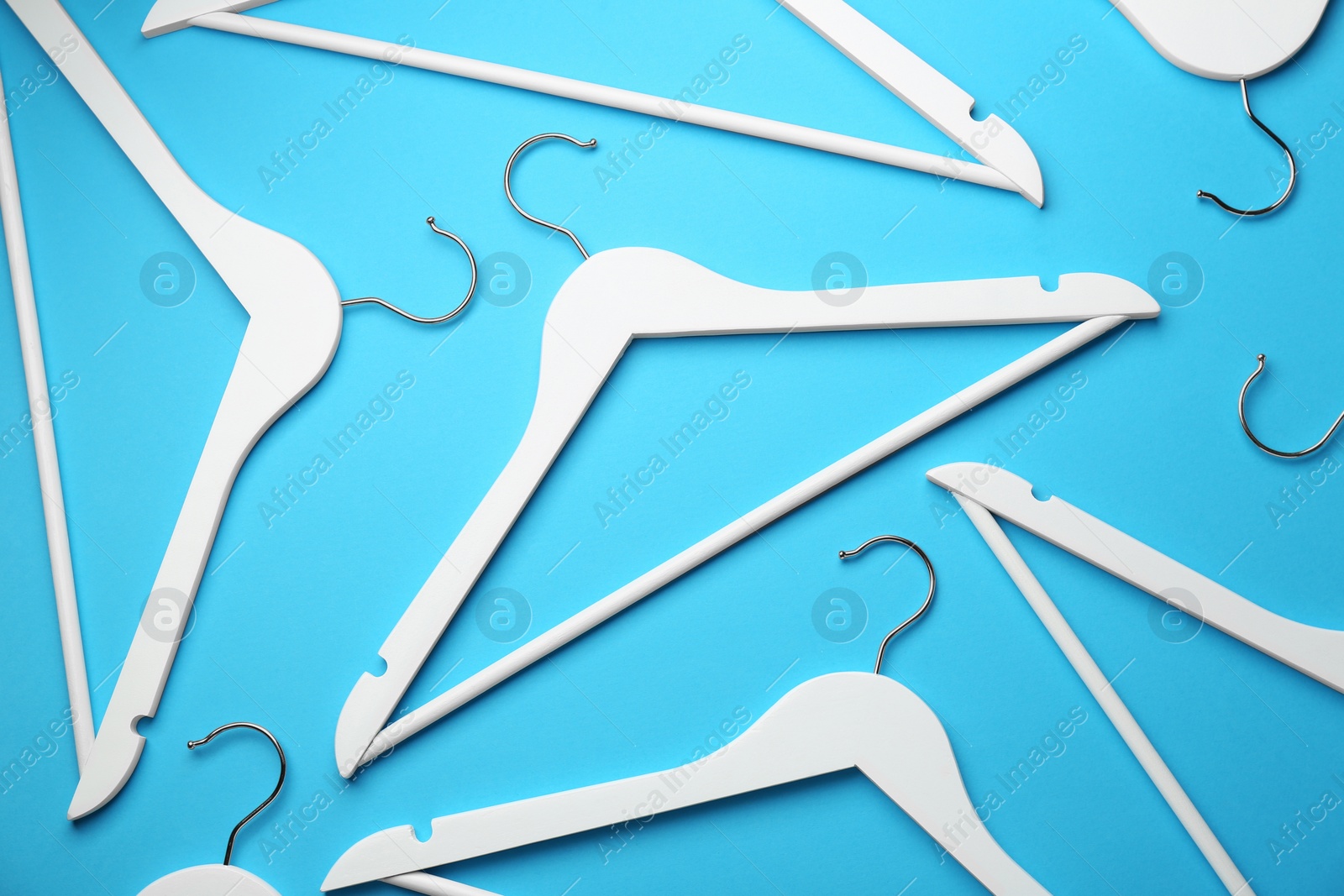 Photo of White hangers on light blue background, flat lay