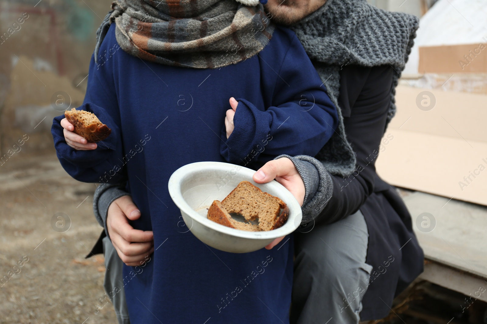 Photo of Poor father and child with bread at dump, closeup