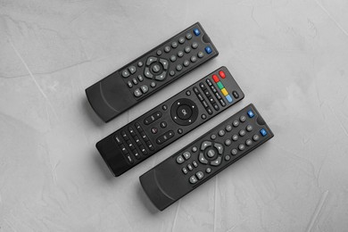 Photo of Modern tv remote controls on grey table, flat lay