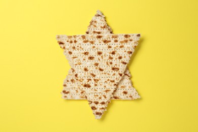 Photo of Star of David made with passover matzos on yellow background, top view