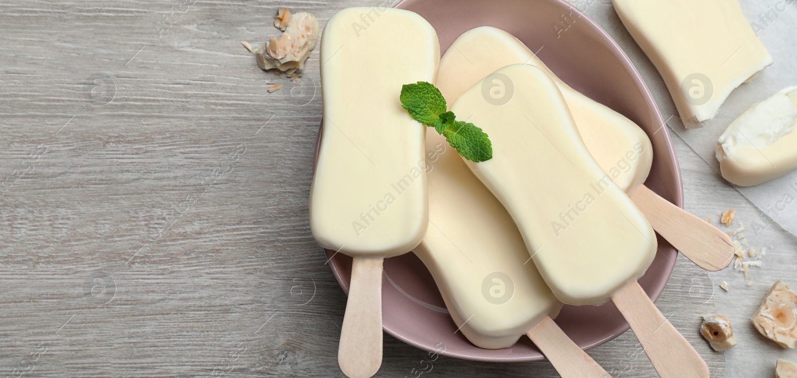 Image of Delicious glazed ice cream bars, chocolate and mint on white wooden table, flat lay with space for text. Banner design