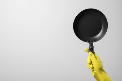 Woman holding empty frying pan on white background, closeup. Space for text