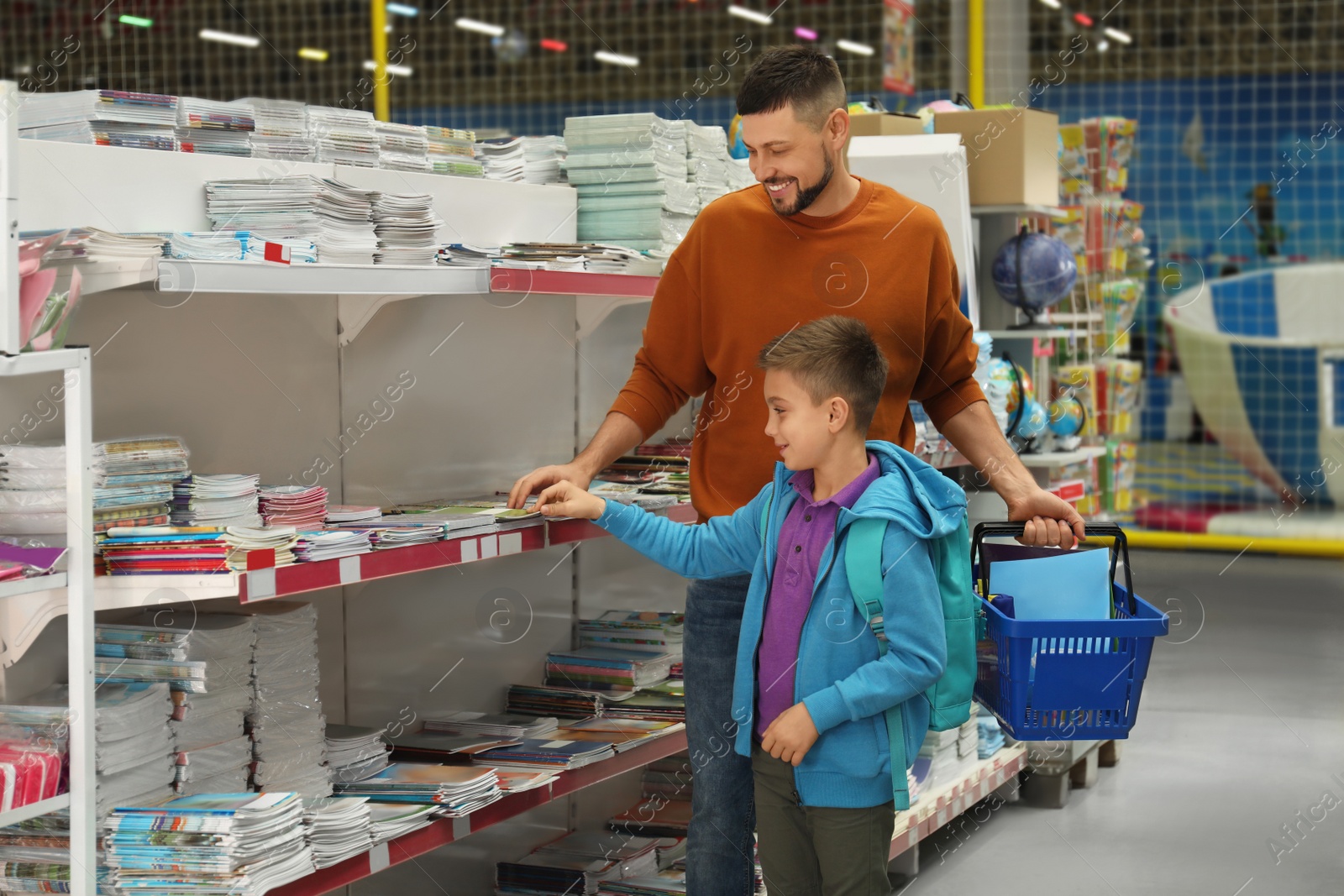 Photo of Little boy and father choosing school stationery in store