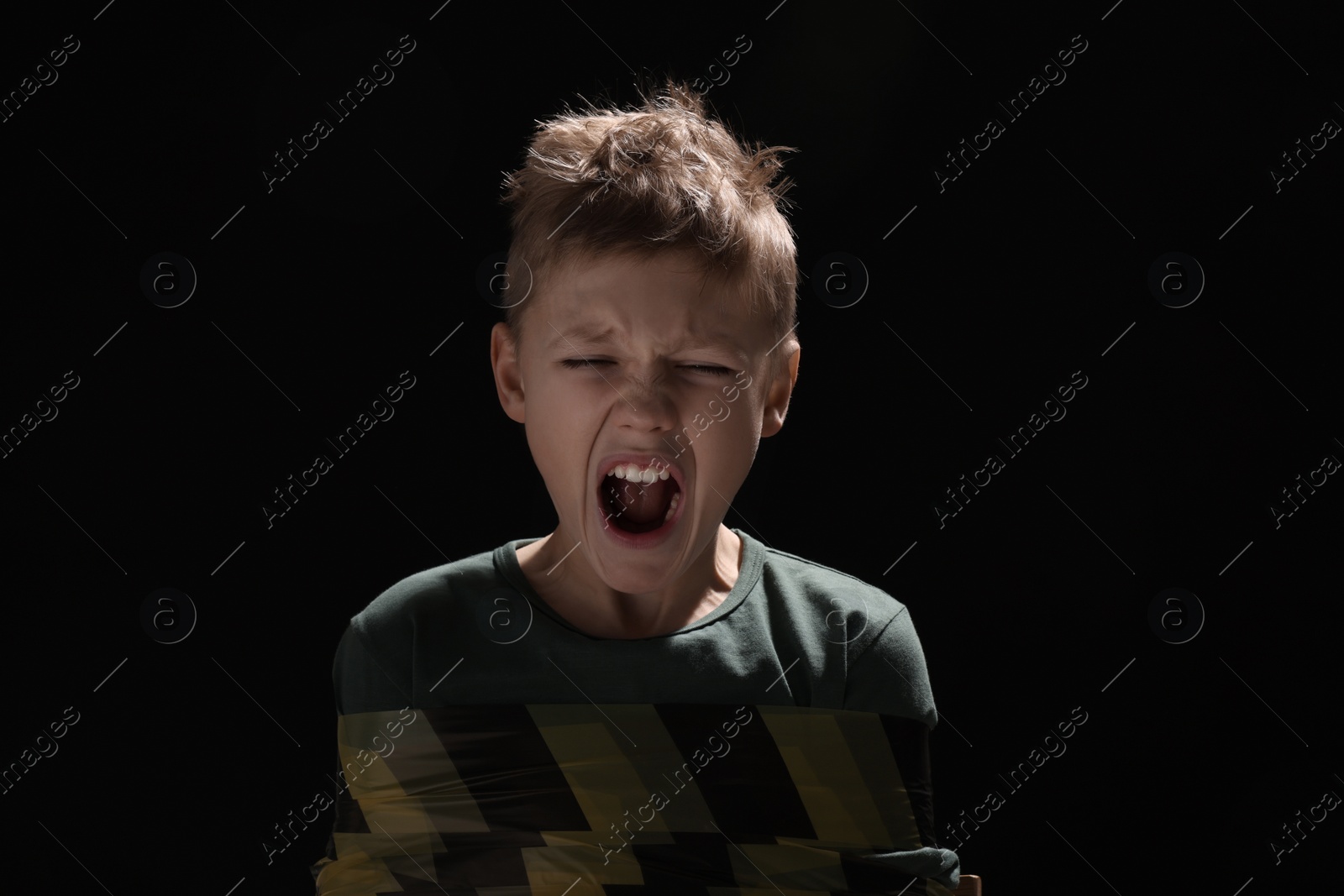 Photo of Scarred little boy tied up and taken hostage on dark background