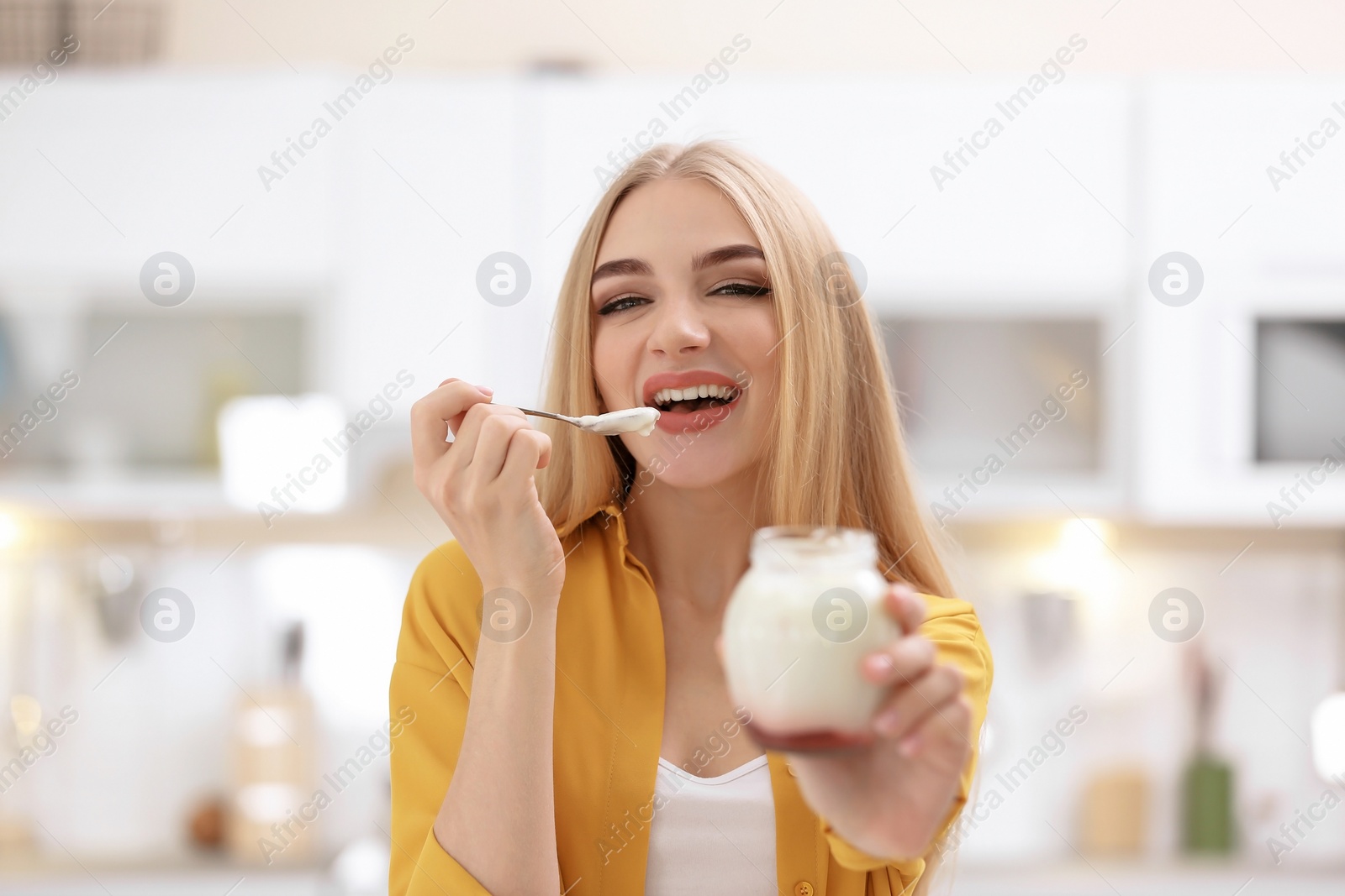 Photo of Young woman with yogurt on blurred background