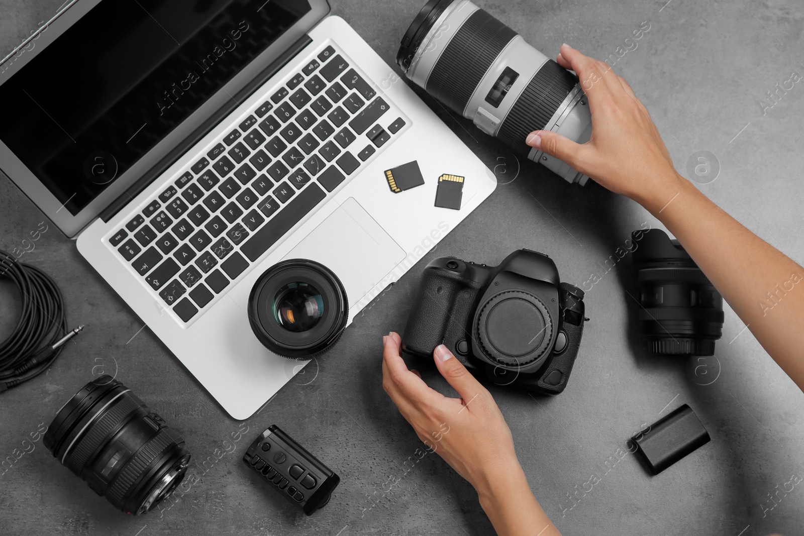 Photo of Woman with professional photographer equipment and laptop at gray table