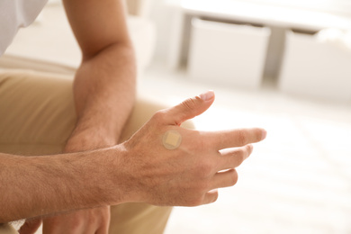 Photo of Man with sticking plaster on hand indoors, closeup