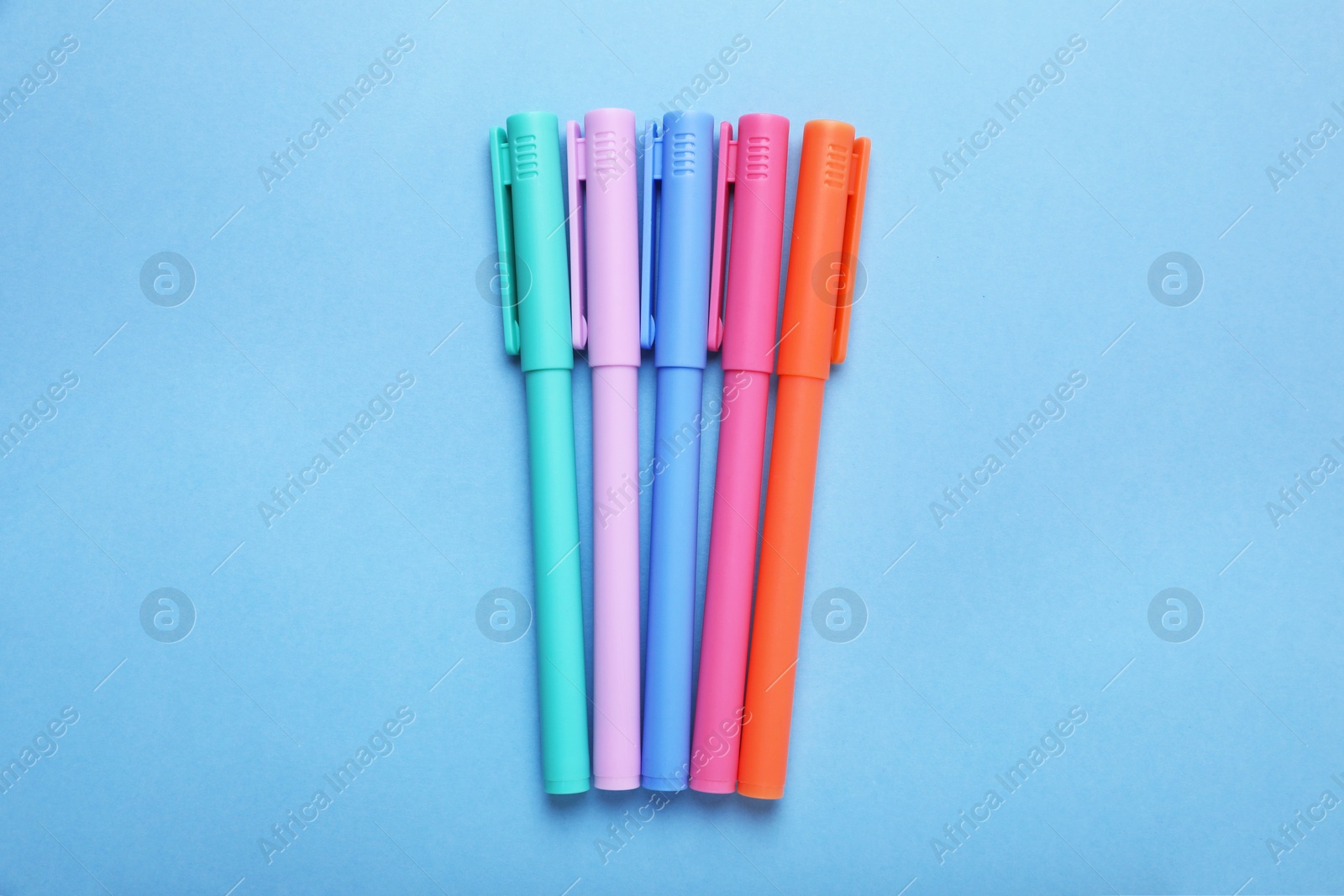 Photo of Many colorful markers on light blue background, flat lay