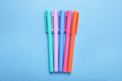 Many colorful markers on light blue background, flat lay