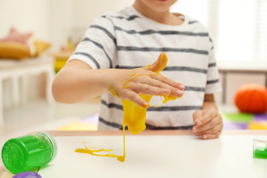 Little boy playing with slime at table indoors, closeup